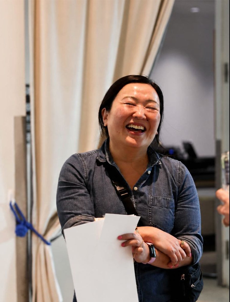 A woman laughing with papers in her hand at a Malone event