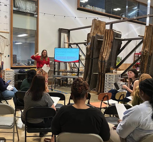 A workshop leader presenting to a seated group at Women Building Creative Futures