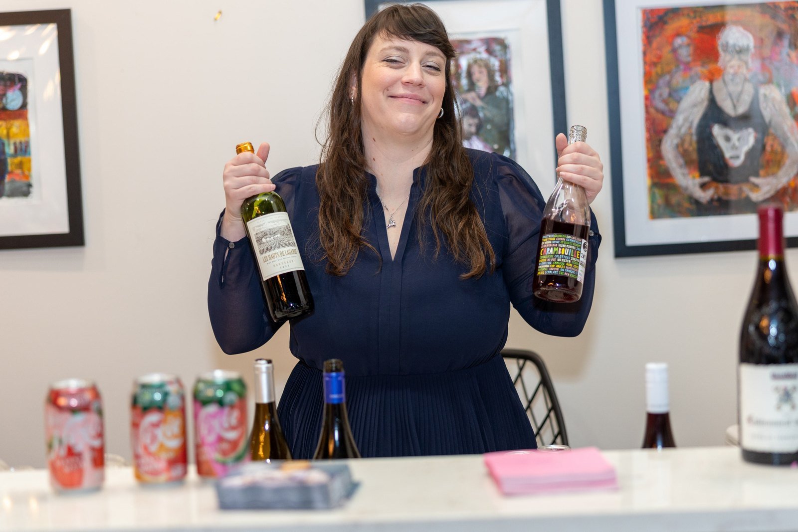 A woman holding up two bottles behind a market table