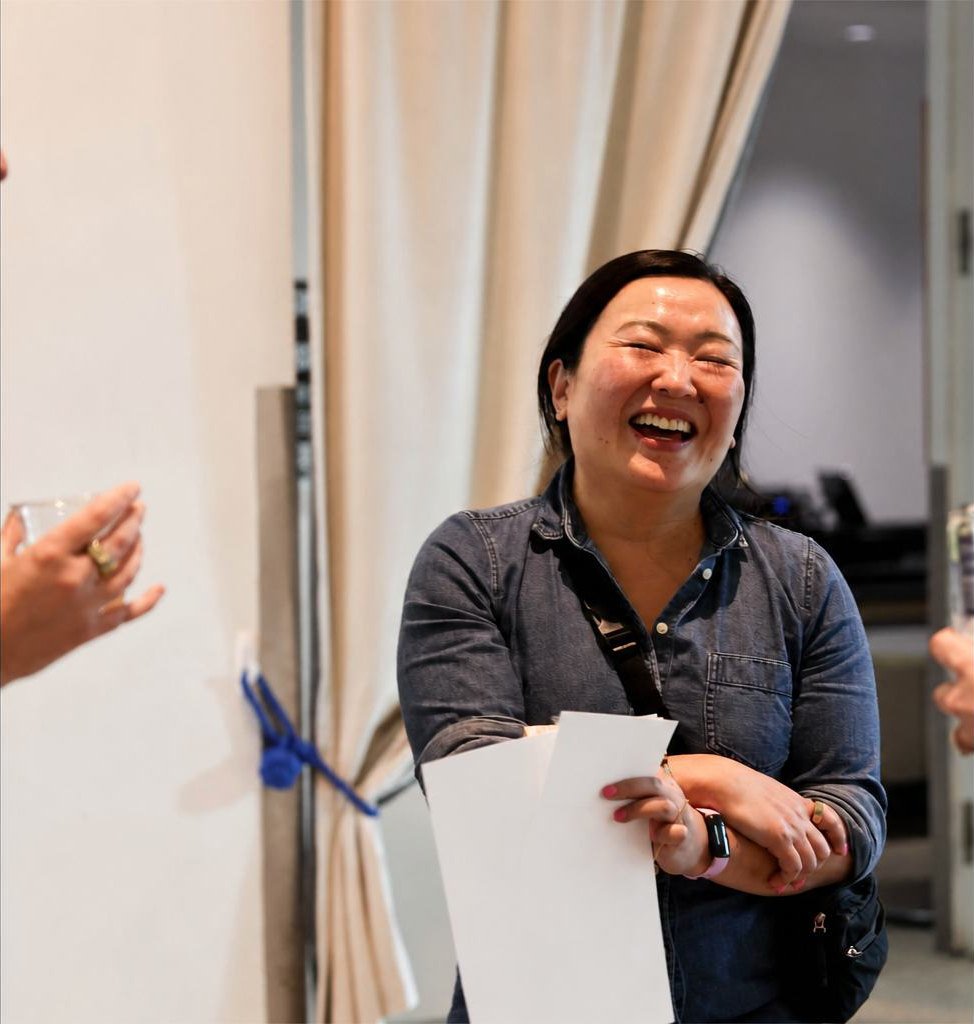 A woman laughing while holding handouts at a workshop