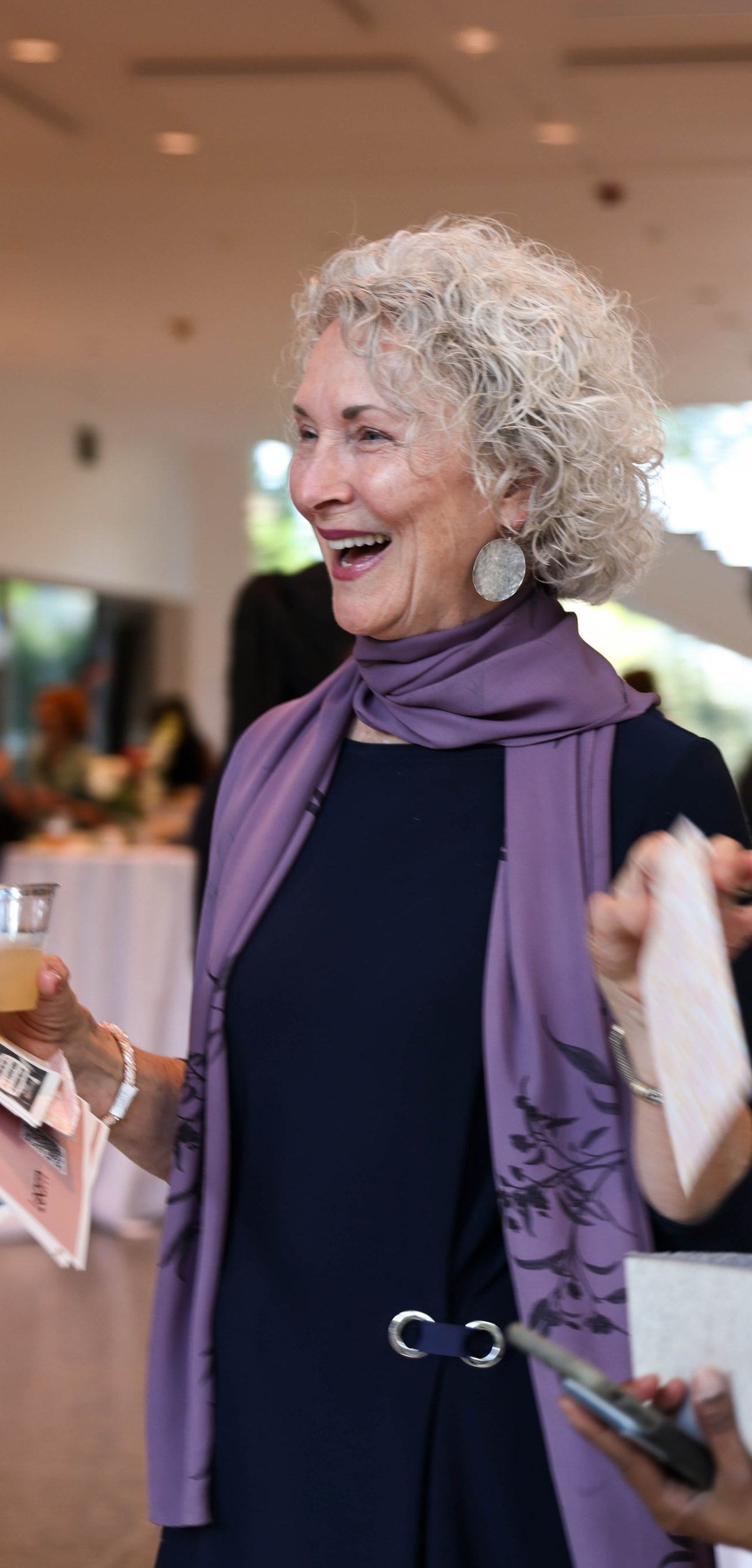 A woman laughing while talking with someone at a Malone event